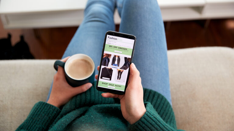 Nahaufnahme aus Sicht einer Frau, die ein Smartphone verwendet, um online Kleidung einzukaufen.