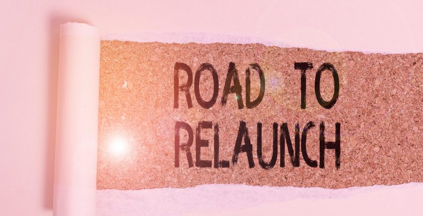Conceptual hand writing showing Road To Relaunch. Concept meaning In the way to launch again Fresh new start Beginning Cardboard which is torn placed above a wooden classic table